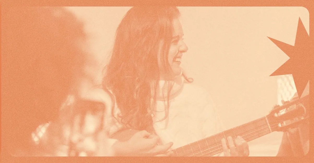 Mulher tocando violão e sorrindo durante ensaio musical, representando dicas para ministério do louvor com foco em prática e dedicação.